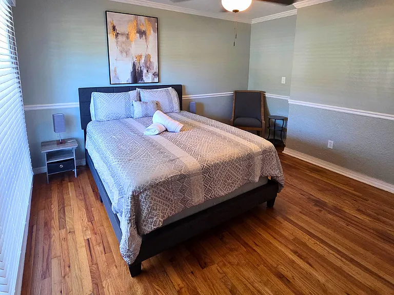 Large window with elegant blinds fills the bedroom with natural light.
