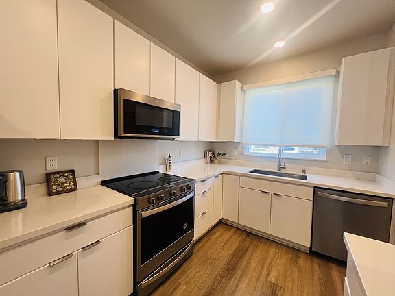 Modern kitchen featuring a large sink, stainless steel range, microwave, and dishwasher, complemented by ample counter space for your culinary needs