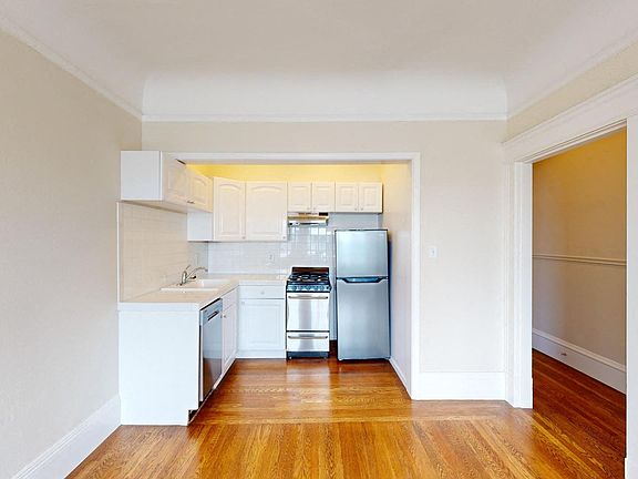 Kitchen with multiple cabinets, refrigerator, stove, range hood, and sin