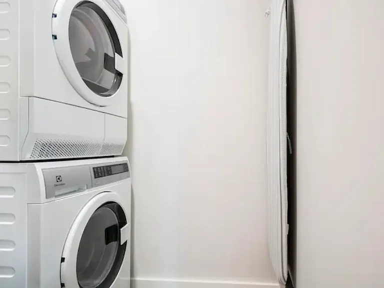 The washer and dryer are located in a walk-in, pocket-door closet in the entry area. There is also a mounted ironing board.