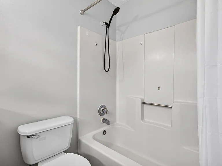 Full bath with tub/shower combo, handheld showerhead, and built-in surround shelving for everyday storage.