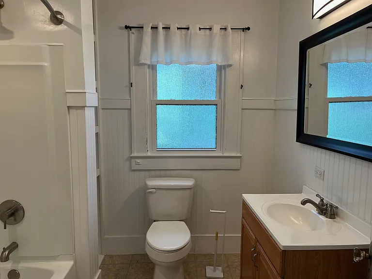 Full bath is accessed from the small hallway off the dining room which also connects the front bedroom and middle bedroom. Rain glass window provides privacy and diffuses light.
