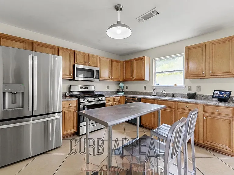 U-shaped kitchen with ample wood cabinetry, stainless appliances, generous counters, and a convenient breakfast table by the
