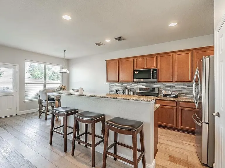 Open-concept kitchen with breakfast bar seating, stainless appliances, and ample cabinetry, flowing into a sunny dining nook.