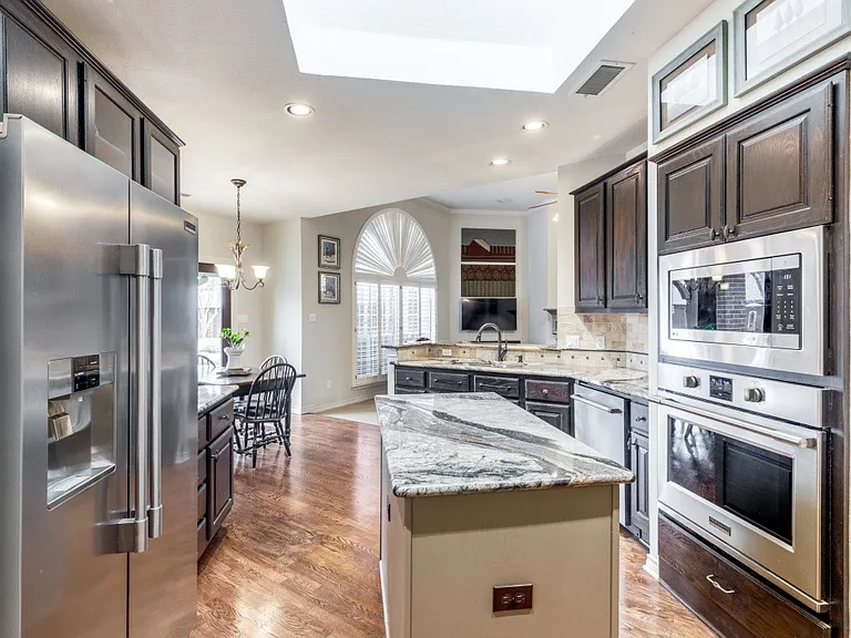 Skylight, decorative light fixtures, a notable chandelier, a kitchen island and stainless steel appliances. Refrigerator stays.