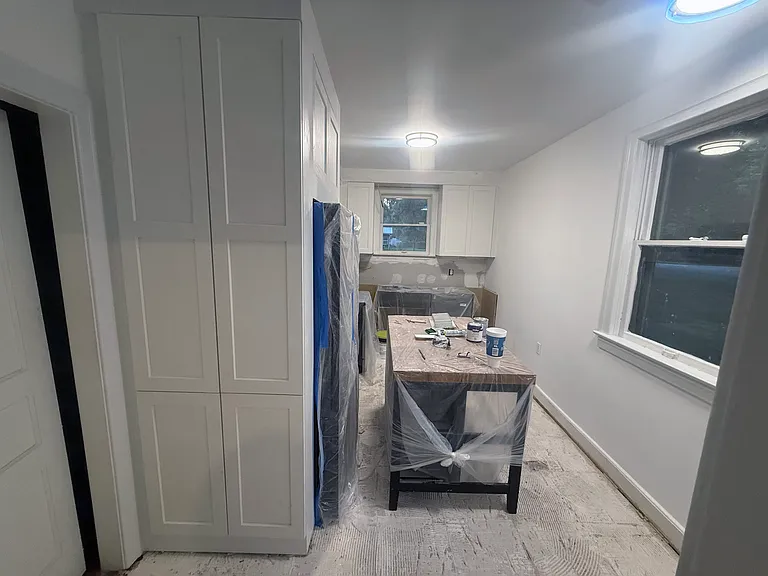 Kitchen renovation in progress before installation of new floors, lower cabinets, countertop, backsplash, cabinet hardware, window treatments