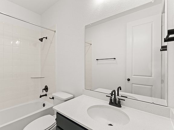 The secondary bath features tile flooring, white cabinetry and light countertops and a shower tub co