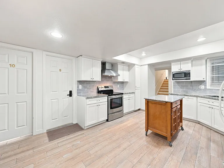 Updated kitchen with ample white cabinetry, stone-look counters, stainless range, and a movable prep island for extra workspa
