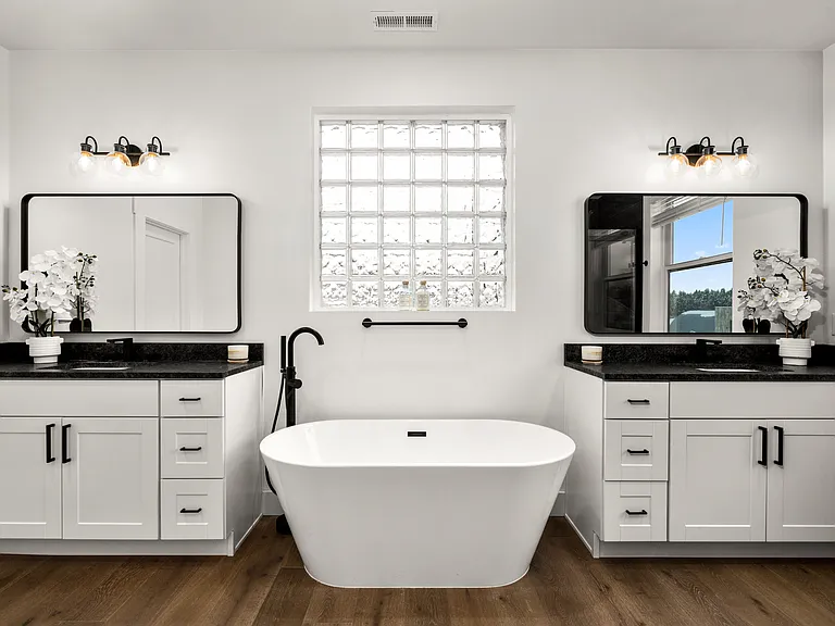 Spa-inspired primary en-suite featuring a luxurious soaking tub, dual vanities, elegant finishes, and a serene atmosphere designed for peaceful retreat and everyday indulgence.