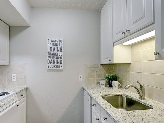 Kitchen features granite countertops and tile backsplash.