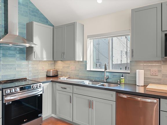 New kitchen with stainless appliances and tile backsplash.