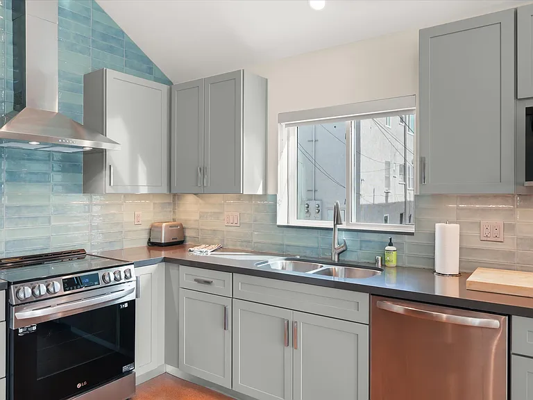 New kitchen with stainless appliances and tile backsplash.