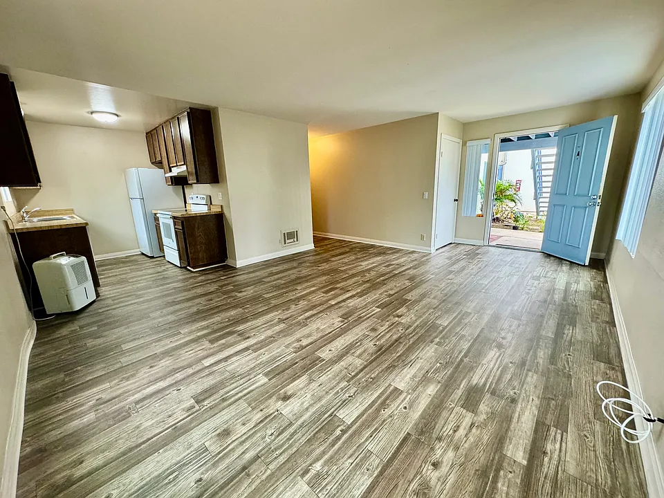 View from living room into kitchen and front door with entrance closet