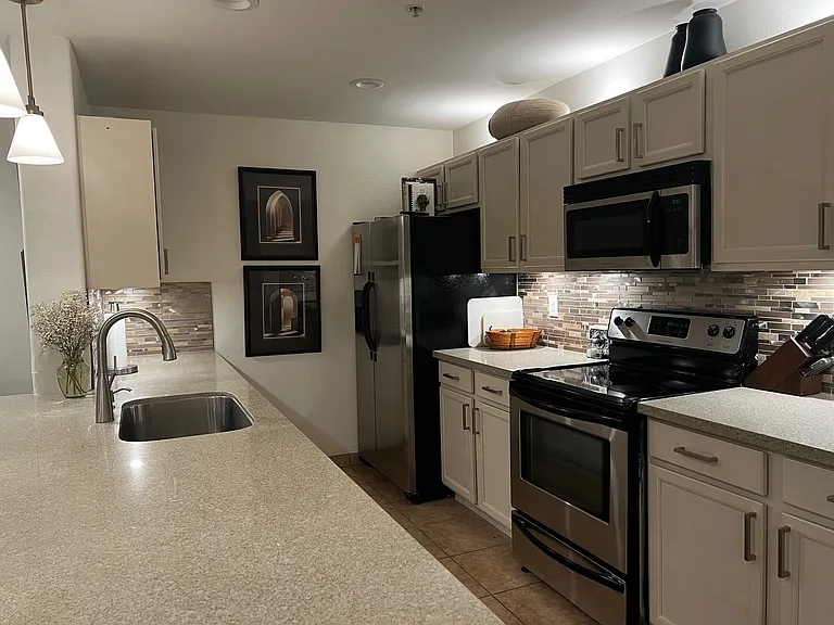 Remodeled kitchen with quartz oversized counter, under-counter lighting, glass backsplash, new appliances, new hardware and light cabinetry