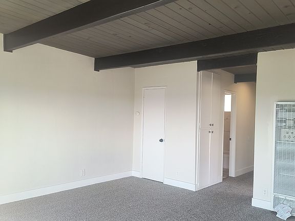 Spacious living room with new dual pane slider to private balcony water view. (Upper floor vaulted wood beam ceiling)