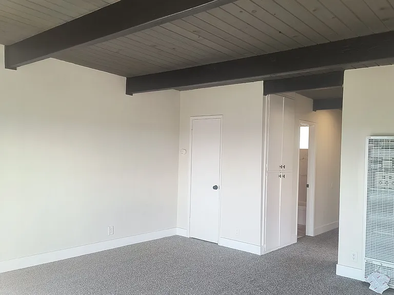 Spacious living room with new dual pane slider to private balcony water view. (Upper floor vaulted wood beam ceiling)