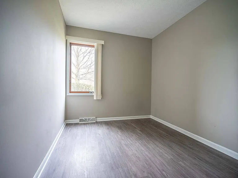 View of typical second bedroom with window and faux plank flooring