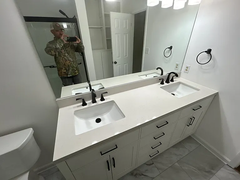 This is renovation project manager Nathan proudly taking a photo of his team's work in the master bathroom, which features a 72" double-sink vanity, toilet, LVT flooring and a walk-in shower.