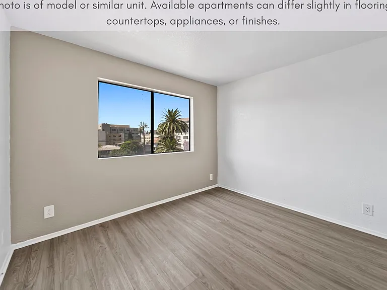 Spacious bedroom with modern flooring and scenic neighborhood views.