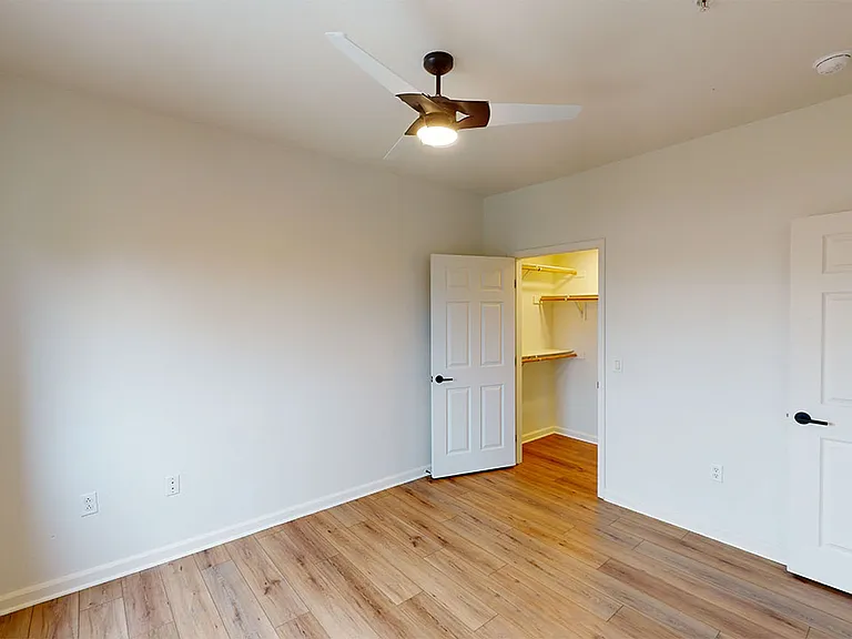 Spacious apartment bedroom with large closet and wood-style flooring.