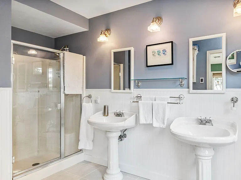 En-suite bathroom with double sinks and medicine cabinets for storage.