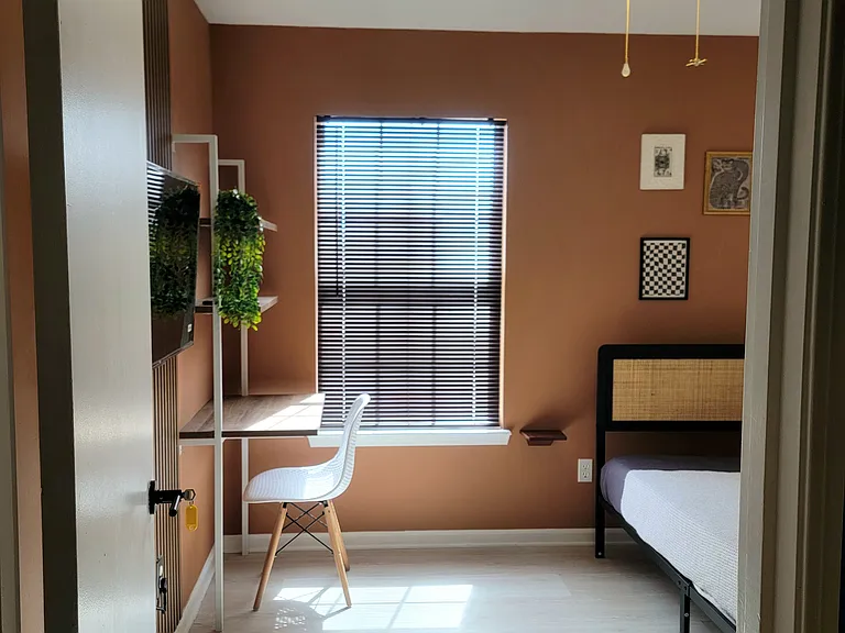 Bright private bedroom with desk, large window, and natural light.