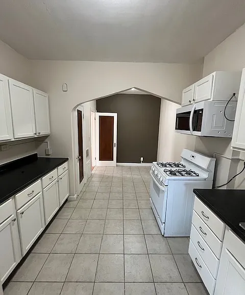 Kitchen view from the back entrance. New cabinets, microwave, countertops. Arch and accent wall in dining area