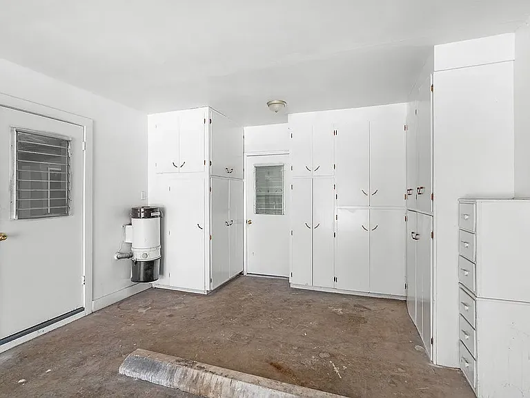 View of inside of garage showing door into kitchen, Utility room, and extensive storage cabinets