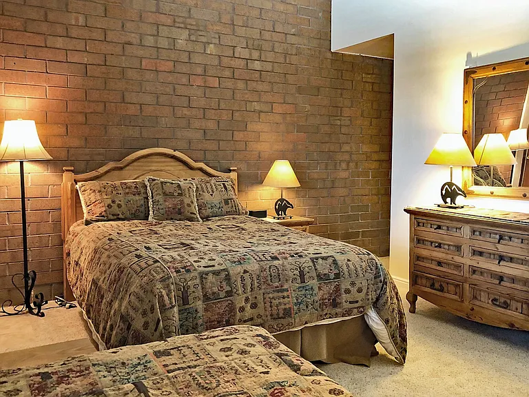 The master bedroom has both a queen with an outdoor stairway exit on the left and a hallway leading to the other bedroom and the downstairs on the right.