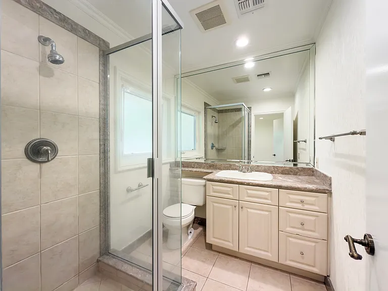 Tiled glass shower and a granite vanity with a large mirror complete this full bath in a Beverly Hills luxury rental at 1094 Garden Lane, 90210.