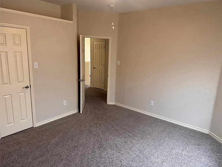 Bedroom featuring textured carpeting, neutral wall finishes, and white trim