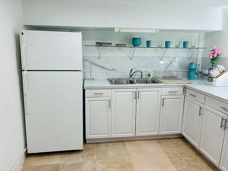 Clean, functional kitchen with full-size refrigerator, double-basin sink, ample cabinetry, and generous counter space.
