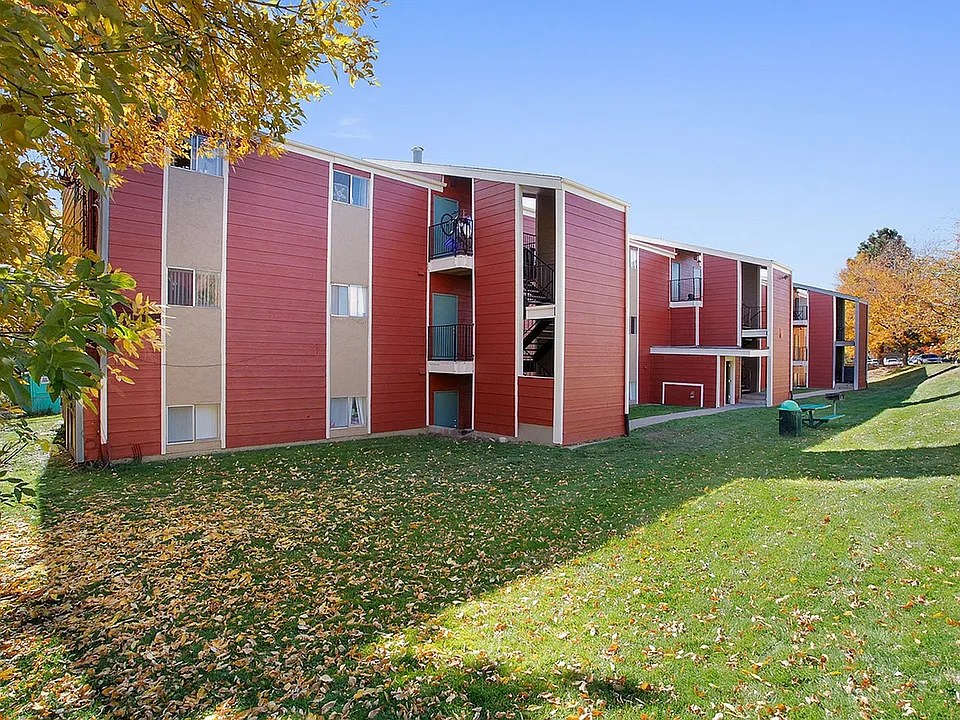 Charming red-brick apartment complex with lush green lawns and vibrant autumn trees.