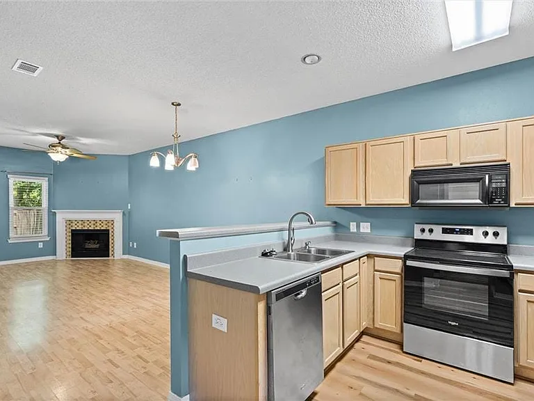 Kitchen featuring wood-finish cabinetry, stainless steel appliances, and a double basin sink