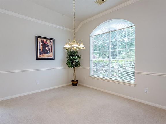 Spacious dining room offers high ceilings, crown molding, chair rail and large arched window with views of the front lawn.