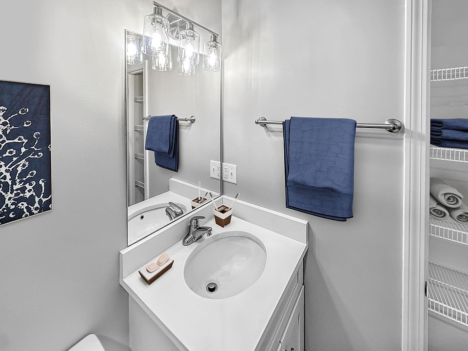 bathroom showcasing modern fixtures, a sleek white vanity, and plush blue accents, creating an inviting and fresh atmosphere.