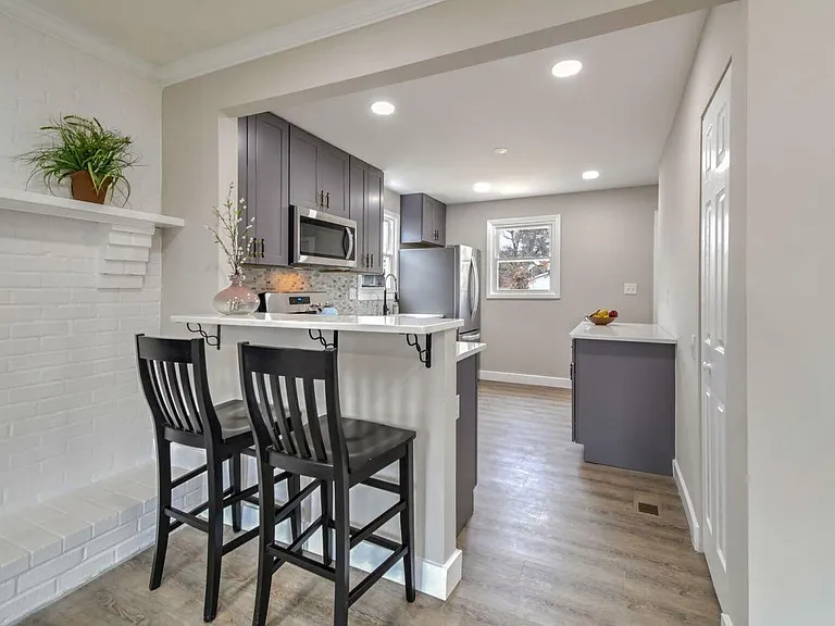 Open kitchen with breakfast bar seating, stainless appliances, and ample cabinet storage, plus a nearby pantry nook.