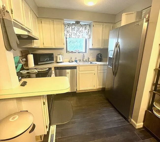 Kitchen with light cabinetry, dark flooring, and modern appliances.
