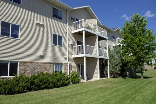 The exterior of Amber Fields, showcasing the green lawn and views of the balconies and patios - Amber Fields Apartments
