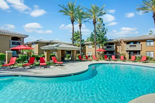 An outdoor pool with lounge chairs and palm trees - Reserve at Arrowhead