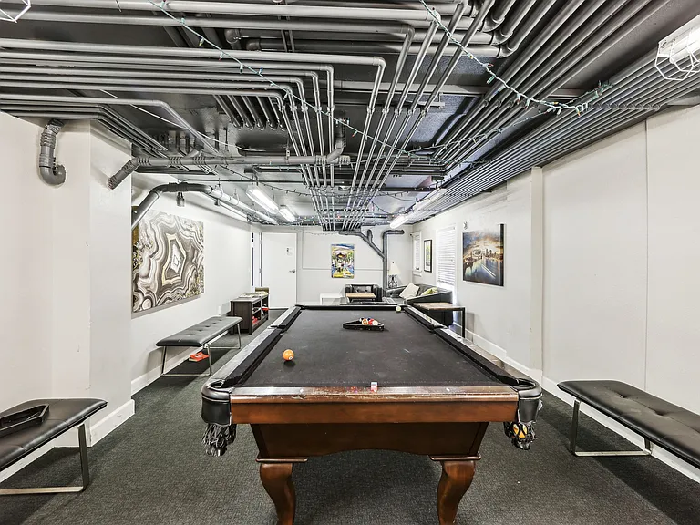 Basement room with pool table surrounded by a couch and a bench
