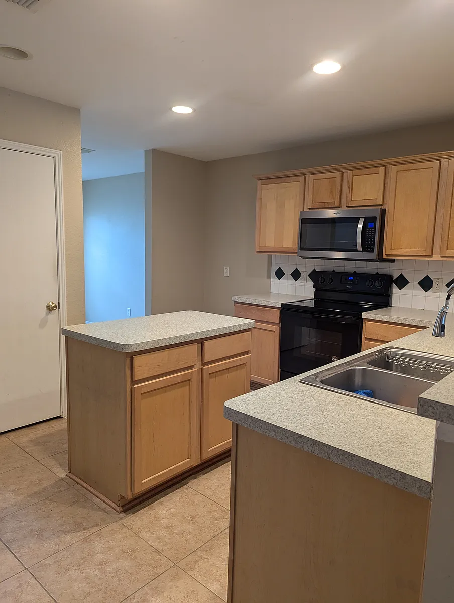 Kitchen with island. Formal dining room is in front of the house through the left entry way. - 8820 Wagon Trl