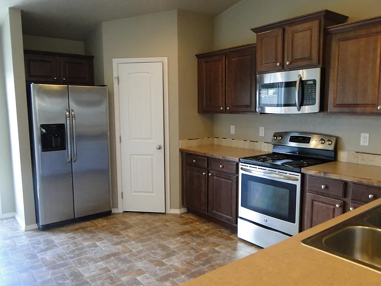 Kitchen view of pantry, fridge , stove and microwave