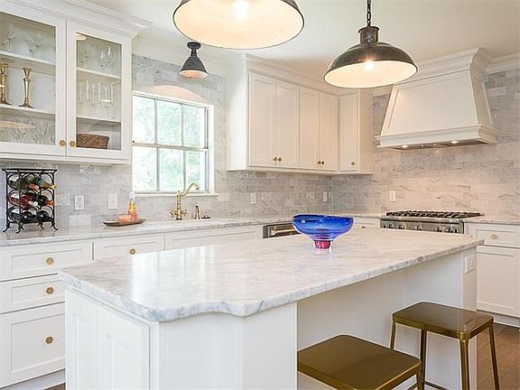 Honed Carrera marble counter tops and back splash in well- equipped kitchen
