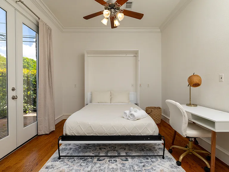 Airy guest room featuring a space-saving bed and patio access.