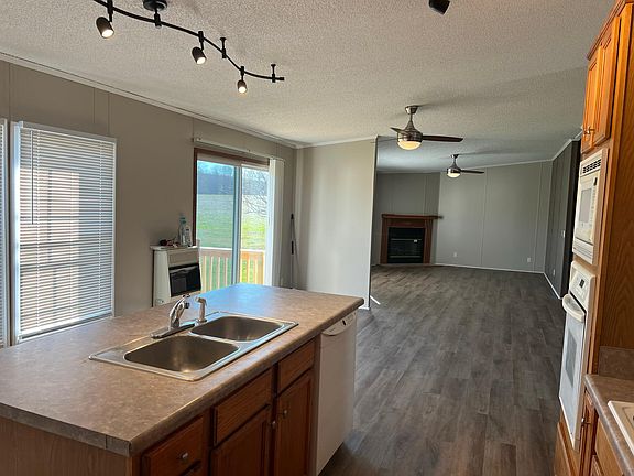View from Kitchen across dining area through to main lounge/living room with fireplace.