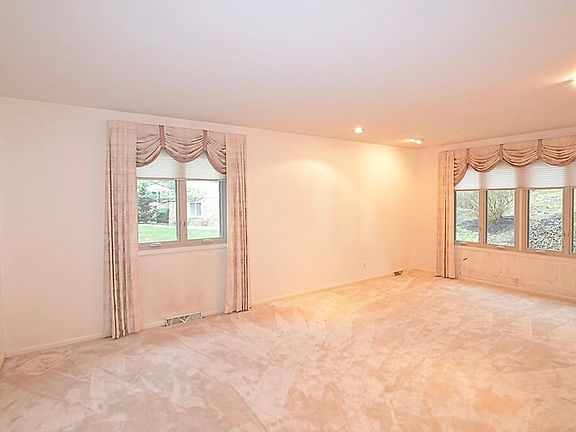 Large sunken formal living room with large windows and views of the wooded lot.