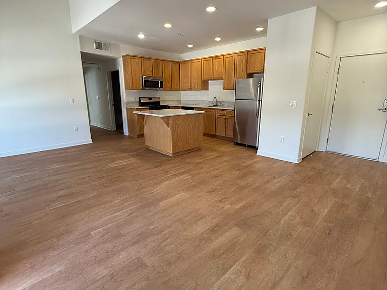 Open area with living room, kitchen with island, dining area, and small closet at entrance. Bonus: High Ceilings