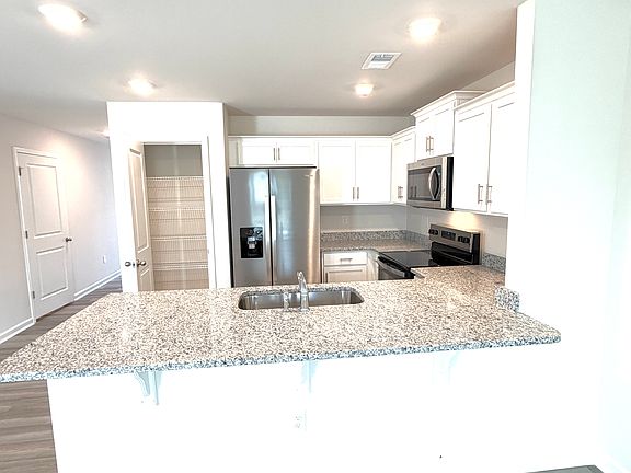 Kitchen features a long island with granite countertops.