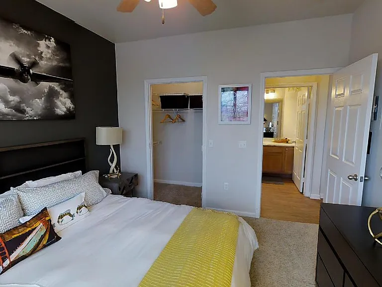 Spacious apartment bedroom with large closet, attached bathroom and plush carpet flooring.